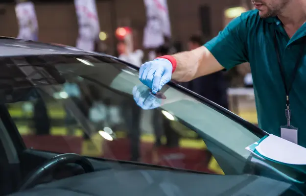 technician-repairing-car-windshield-with-gloved-hand-indoor technician-repairing-car-windshield-with-gloved-hand-indoor