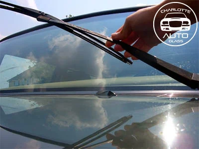 Hand removing a windshield wiper from a car.