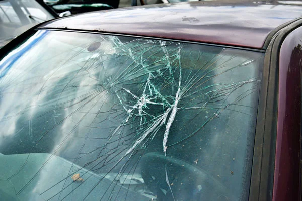 Severely cracked windshield with multiple spreading fractures.