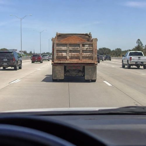 Dump truck carrying dirt driving down multi-lane highway
