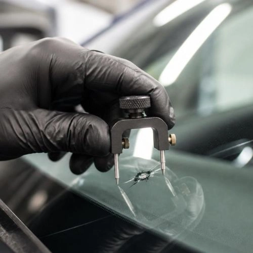 Technician measuring windshield crack damage using tool in Charlotte