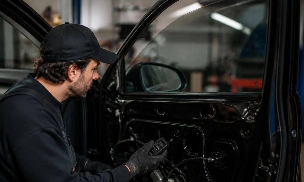 Technician testing the power window switch mechanism inside an exposed car door