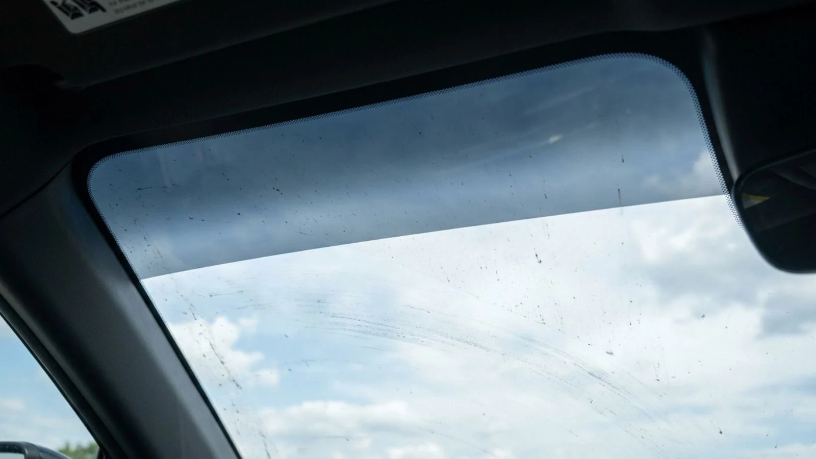 Factory tint band across the top of a windshield seen from the driver seat against daylight sky